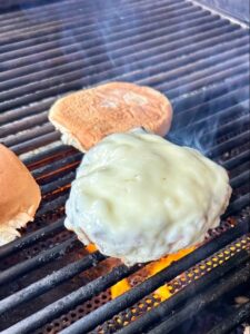 Mama Patierno's Italian Pizza Burger Recipe image of 2 Burgers with Provolone cheese melting on the grill