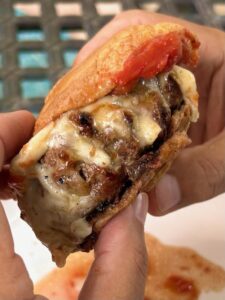 Mama Patierno's Italian Pizza Burger Recipe image of 2 Burgers with Provolone cheese in hand ready to eat